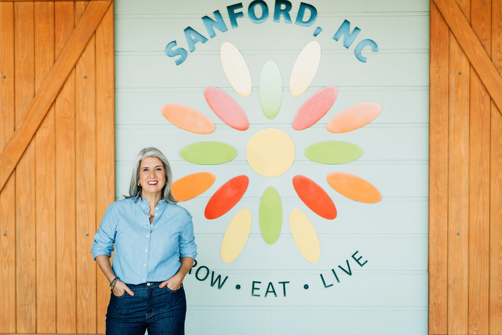 April Montgomery in front of a mural that reads Sanford, NC.